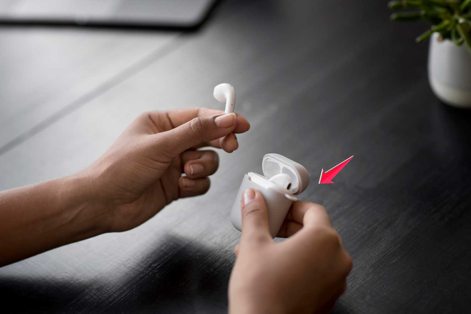 close up hands holding wireless earphones case